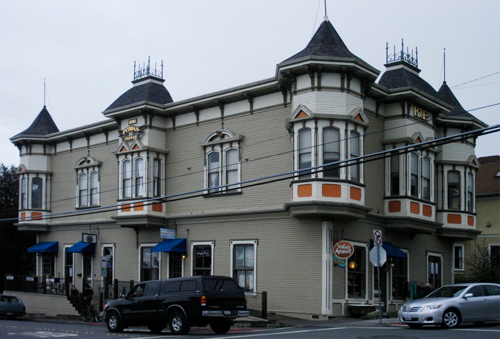 Street photo of a building that resembles a European medieval castle on an urban American street corner.