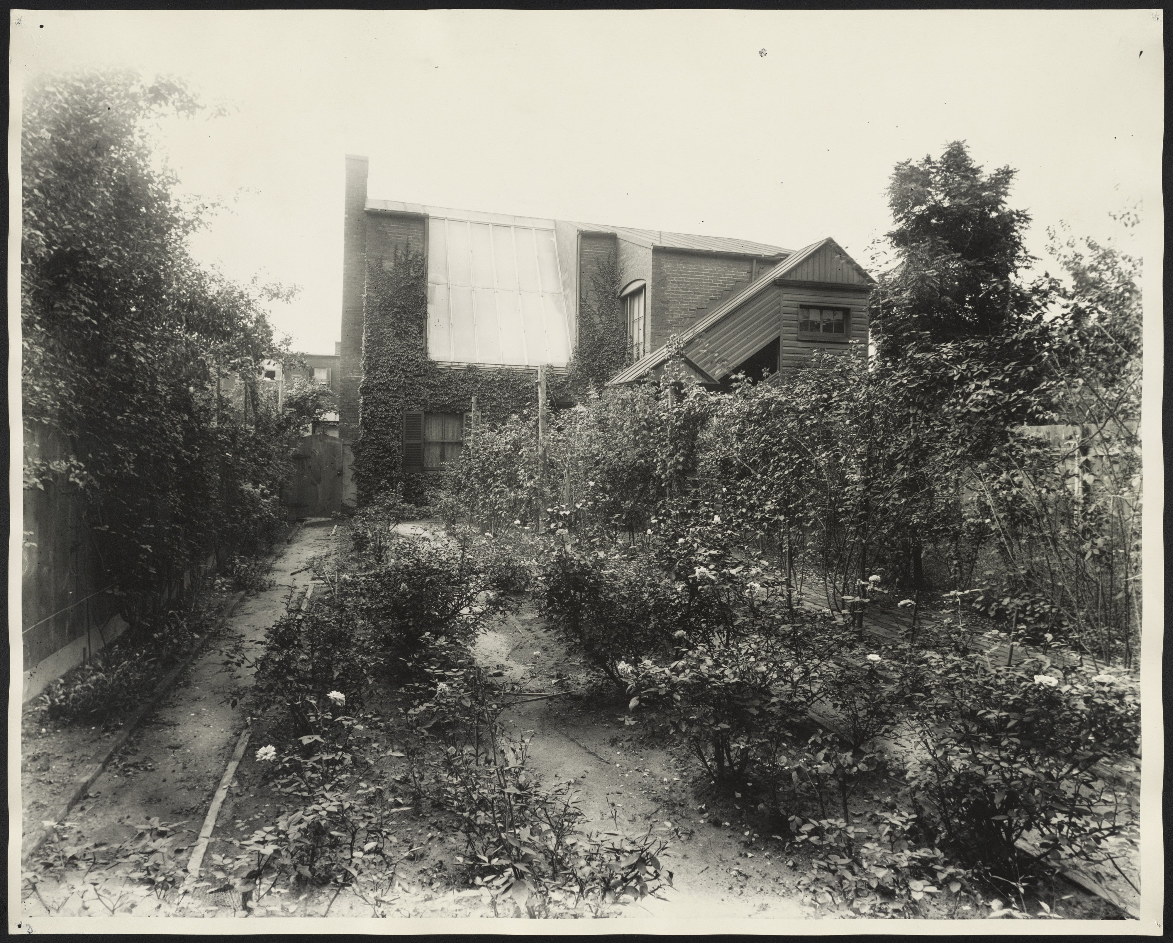 Exterior photo of Frances Benjamin Johnston's home and photo studio in Washington, DC, showing brick building with rose garden. (Source: Library of Congress).