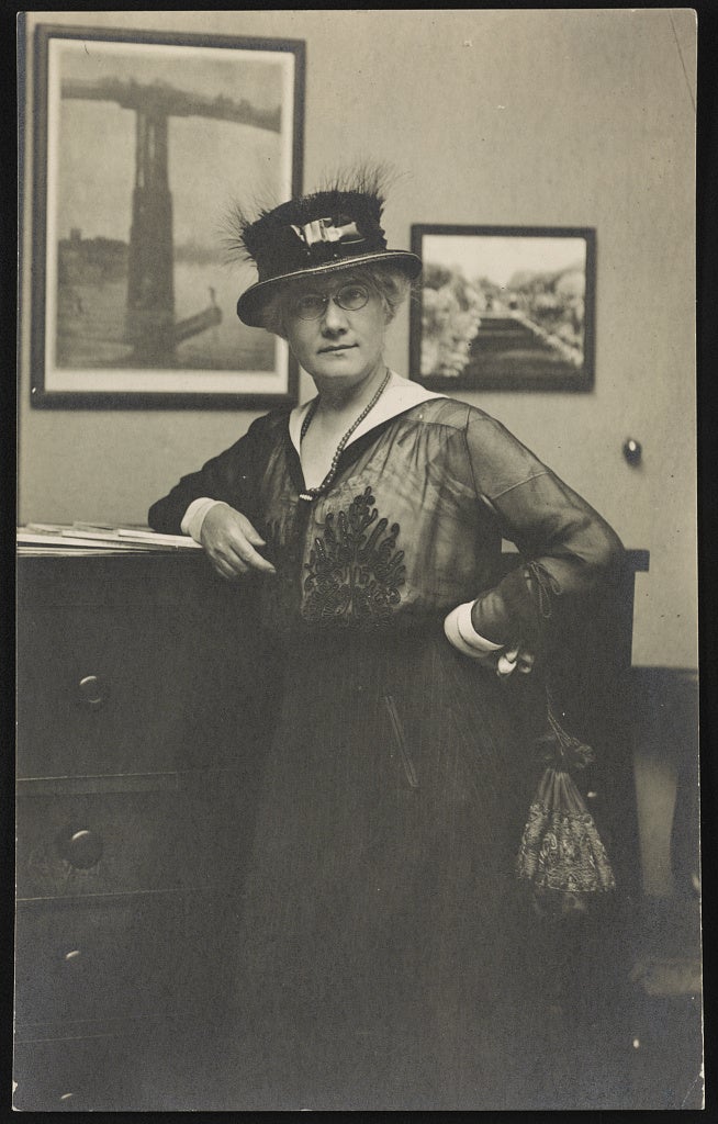 Portrait of Mattie Hewitt leaning against a dresser in a bedroom. 