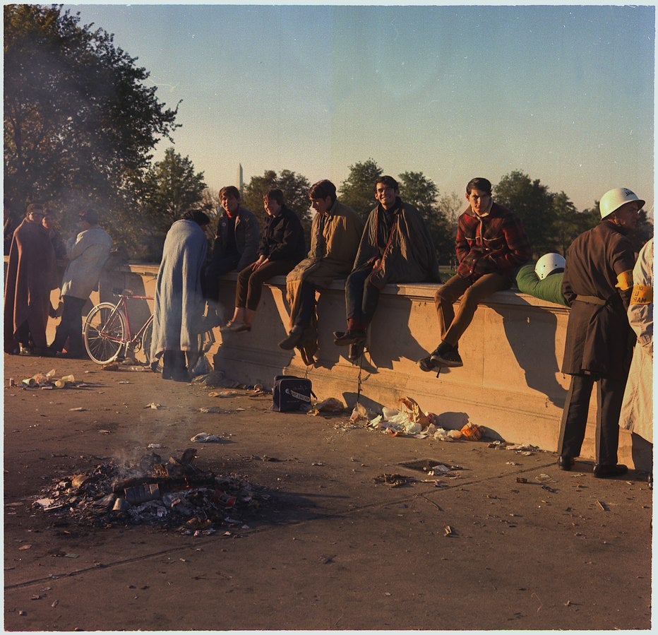 Protesters sit on the wall around their bonfire after spending the night at the Pentagon's mall entrance