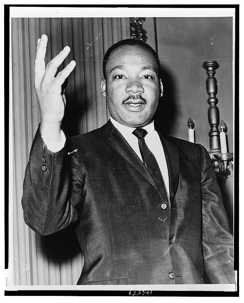 Dr. Martin Luther King, Jr. dressed in a suit and raising right hand. (Source: Library of Congress)