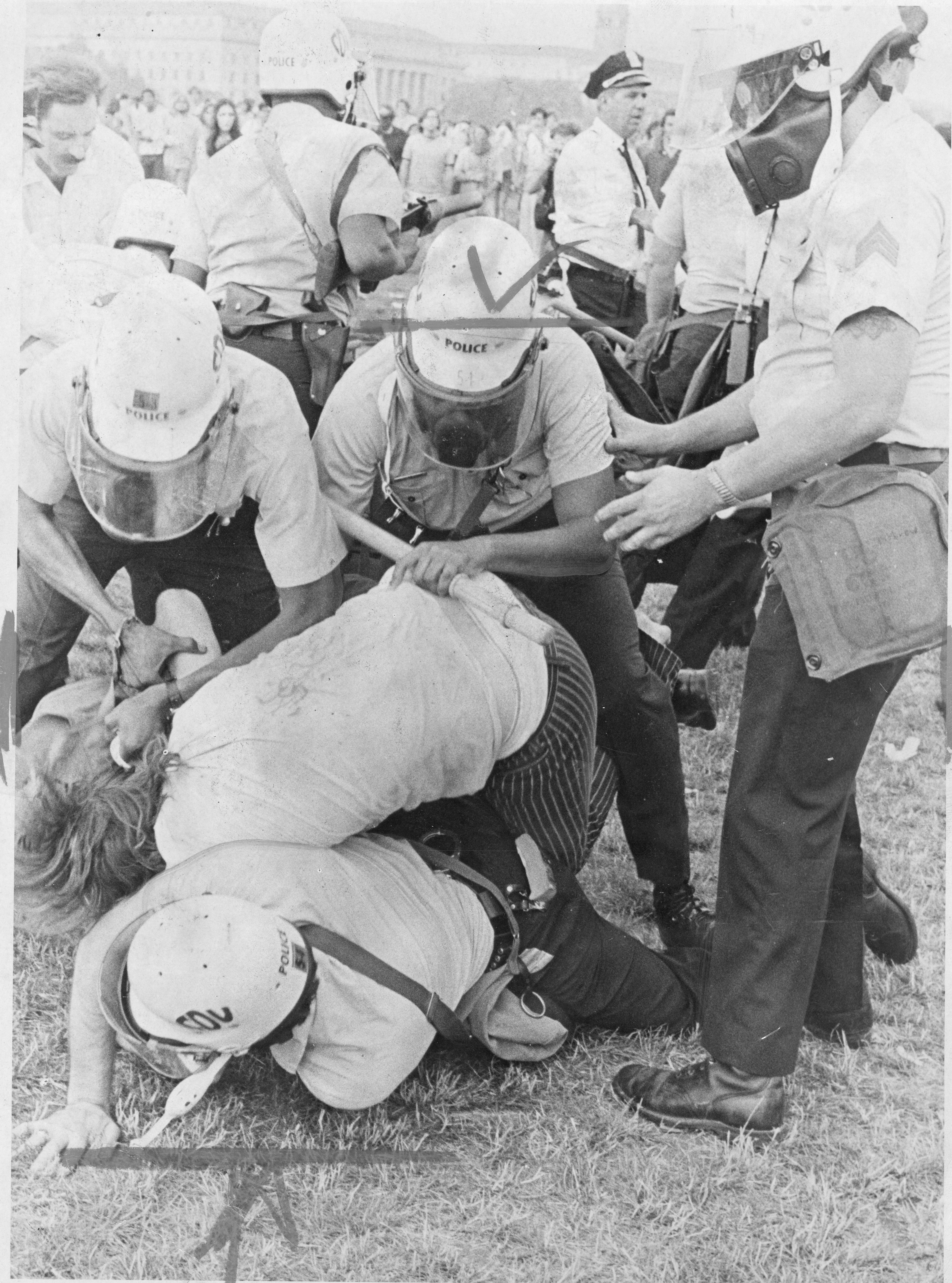 A group of police arrest a Yippie protestor, pushing him to the ground on the National Mall during Honor America Day celebrations. 