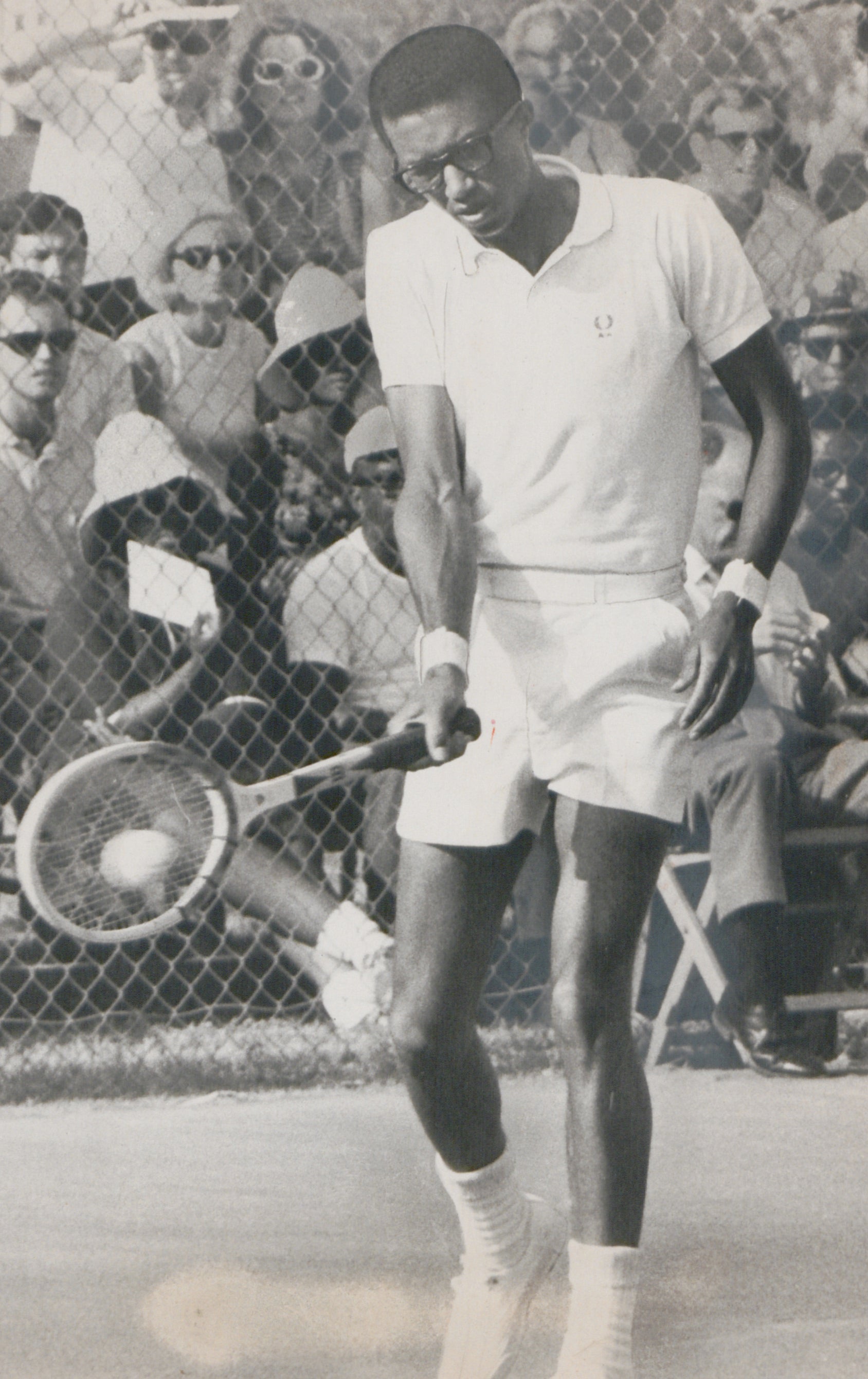 Arthur Ashe during a tennis match. Arthur Ashe hitting a tennis ball with his racket during a match.