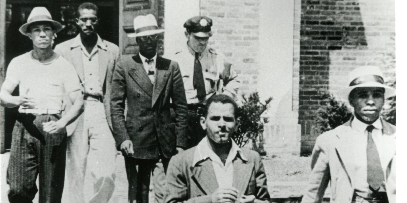 Police officer escorts five young African American men out of the Alexandria, VA Library on August 21, 1939.