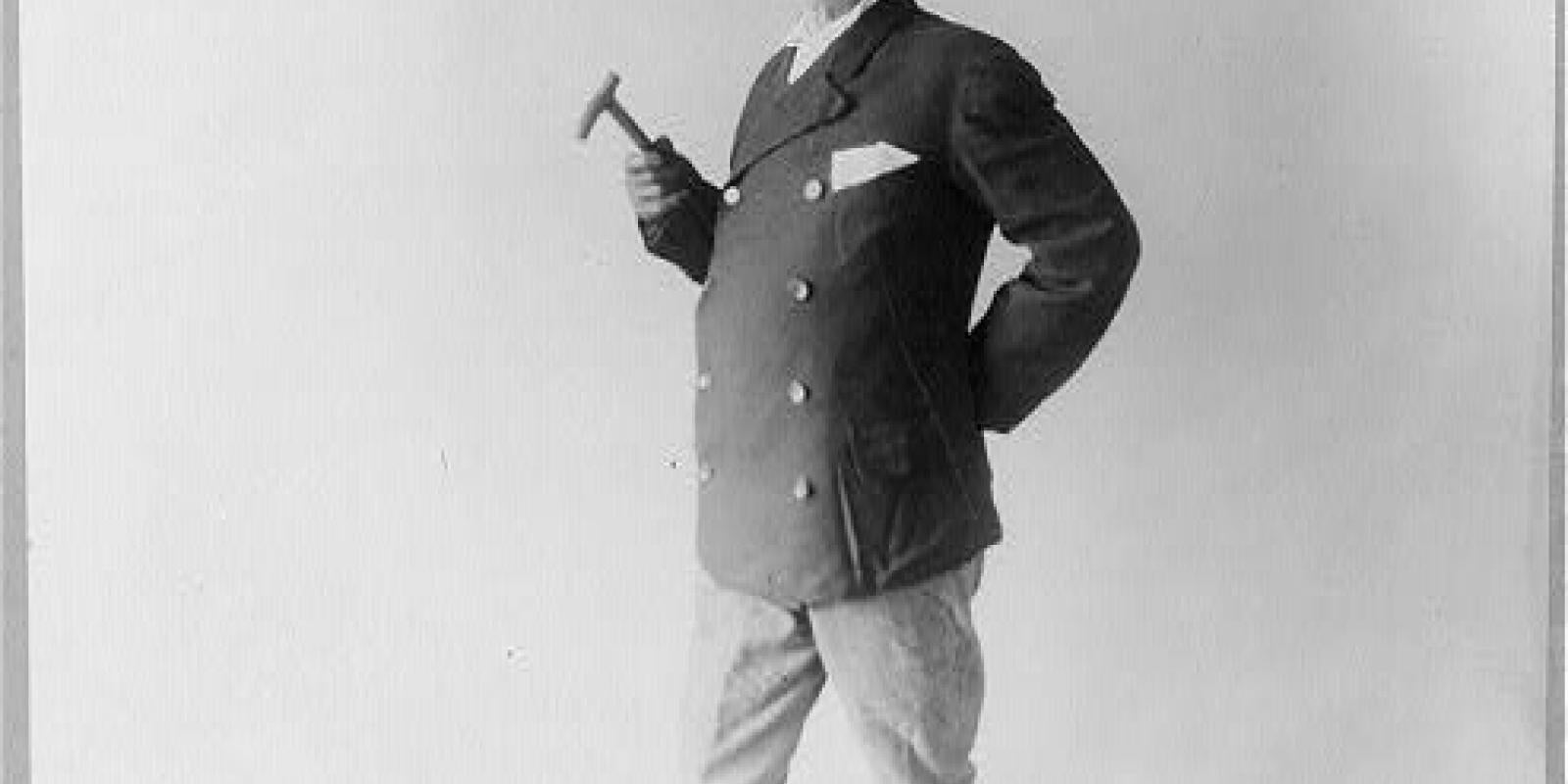 Black and white portrait of Edward Payson Weston looking at the camera holding a cane and wearing a double breasted suit jacket, mid-calf length boots, and a wide brim hat.