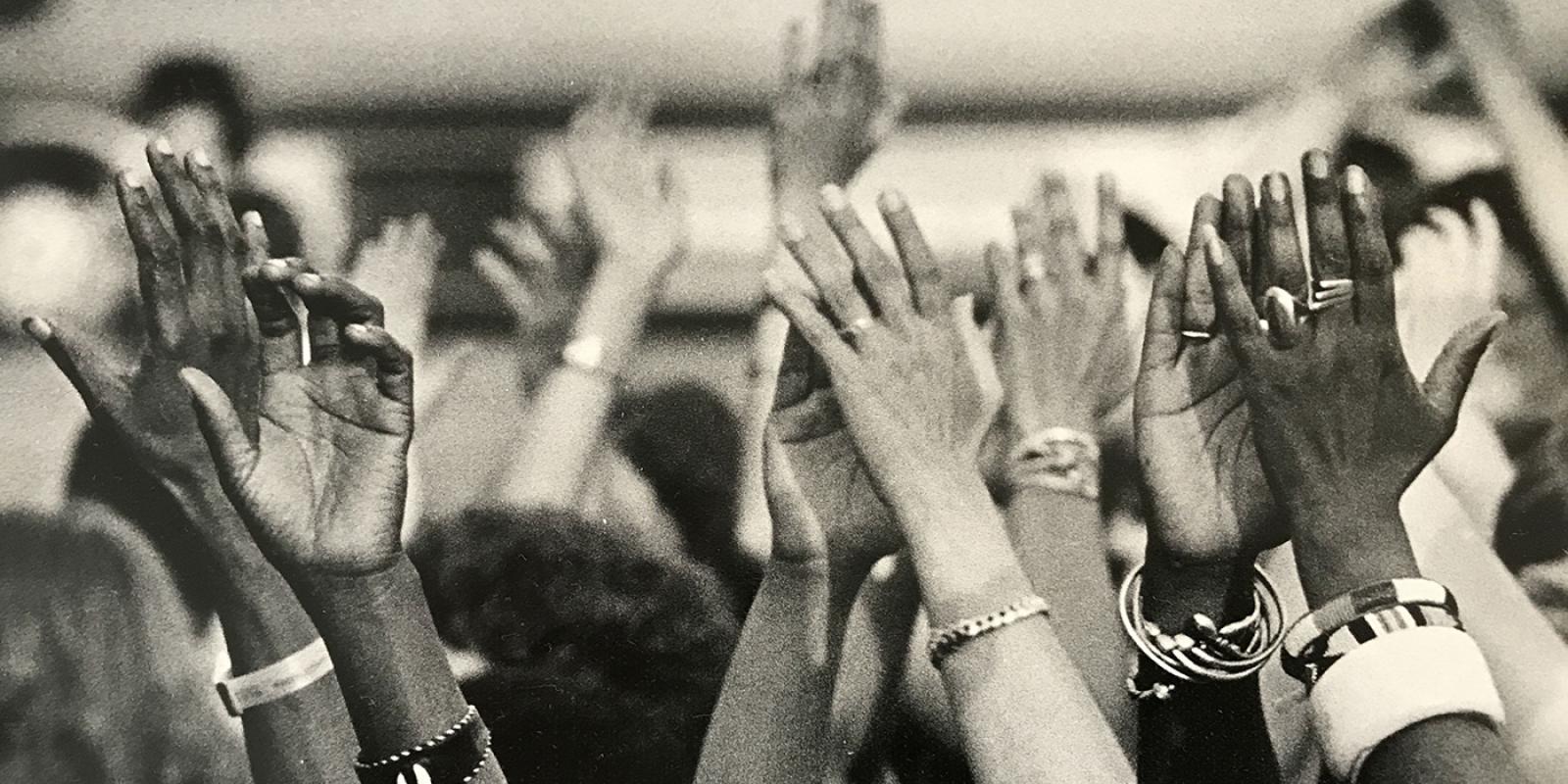 Black and white image of hands reaching up, taken at Sisterfire festival.