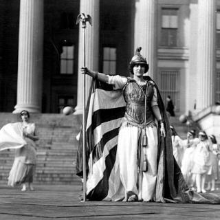 German actress Hedwig Reicher wearing costume of "Columbia" with other suffrage pageant participants standing in background in front of the Treasury Building, March 3, 1913, Washington, D.C. (Source: Library of Congress)