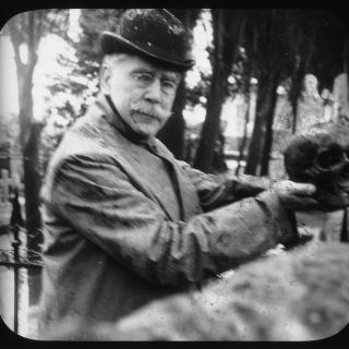 American consul William Bishop holding the skull of James Smithson up to the camera; side profile