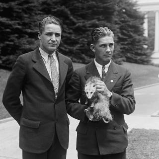 A man and a high school student on the grounds of possibly the White House, holding Billy the possum