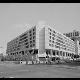 Black and white photo from 1977 of blocky concrete building in downtown D.C. intersection. 
