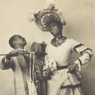Two black actors, Gregory and Brown, one in drag, dancing the Cake-Walk in Paris. Photographic postcard, 1903