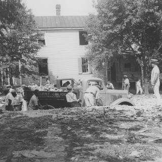 A black-and-white image of men loading debris from a demolished house onto a truck. (Source: National Park Service via Wikimedia Commons)