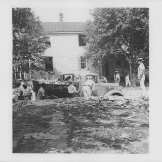 A black-and-white image of men loading debris from a demolished house onto a truck. (Source: National Park Service via Wikimedia Commons)