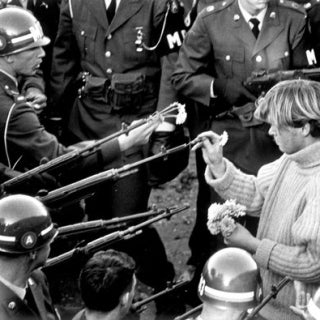  A protester inserts flowers into the rifle barrels of military police near the Pentagon.
