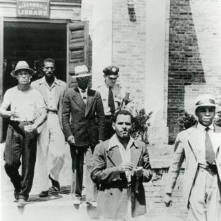 Police officer escorts five young African American men out of the Alexandria, VA Library on August 21, 1939.