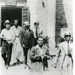 Police officer escorts five young African American men out of the Alexandria, VA Library on August 21, 1939.
