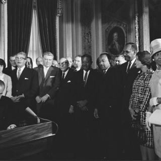 President Lyndon B. Johnson signs the Voting Rights Act while a crowd looks on. Source: Wikimedia
