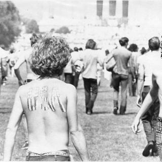 A Hippie walks on the National Mall on Honor America Day with "USA" painted onto his back