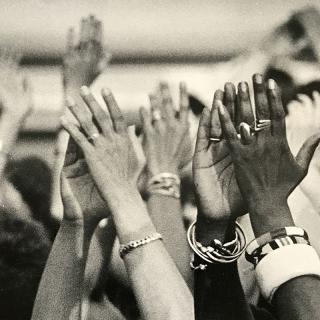 Black and white image of hands reaching up, taken at Sisterfire festival.
