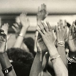 Black and white image of hands reaching up, taken at Sisterfire festival.