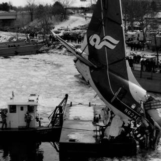 Tail section of wrecked Air Florida plane is lifted above boats on icy river.