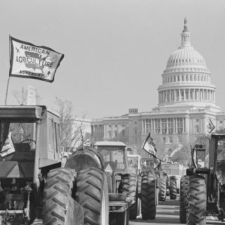 Tractors parked in front of US Capitol, one flying a flag reading "American Agriculture Movement"