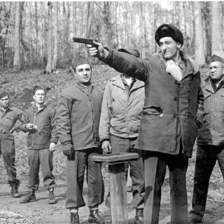 Six OSS recruits watch an instructor shoot a small arm during training at Chopawamsic's Area C. [Source: National Park Service]