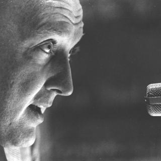 An up close shot of Grant talking into a microphone (1960).