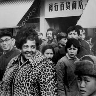 Black female journalist Ethel Payne stands with a smile on her face amidst a crowd in Shanghai, China while she was abroad reporting for the Chicago Defender in the 1970s.