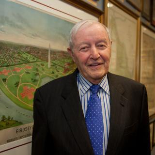 Albert Small in his later years. He stands in front of a  pairing of the National Mall/ 
