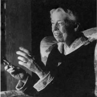 Portrait of Eleanor Roosevelt seated and gesturing with her hands.
