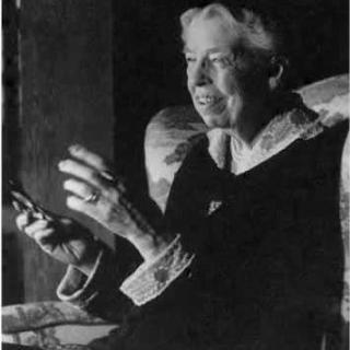 Portrait of Eleanor Roosevelt seated and gesturing with her hands.