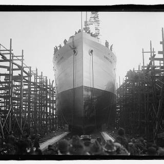 Back of peoples' heads in the foreground with a large boat in the background. 