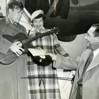 From left to right, Jimmie Dodd and his wife, Ruth, are presented with a record of "Washington" by James H. Simon.