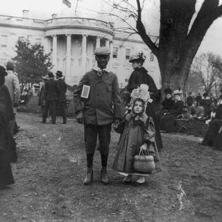 African American boy holding hand of small white girl during Easter egg roll