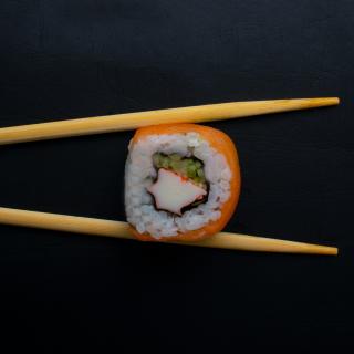 Chopsticks holding sushi roll. (Credit: Mahmoud Fawzy on Unsplash)