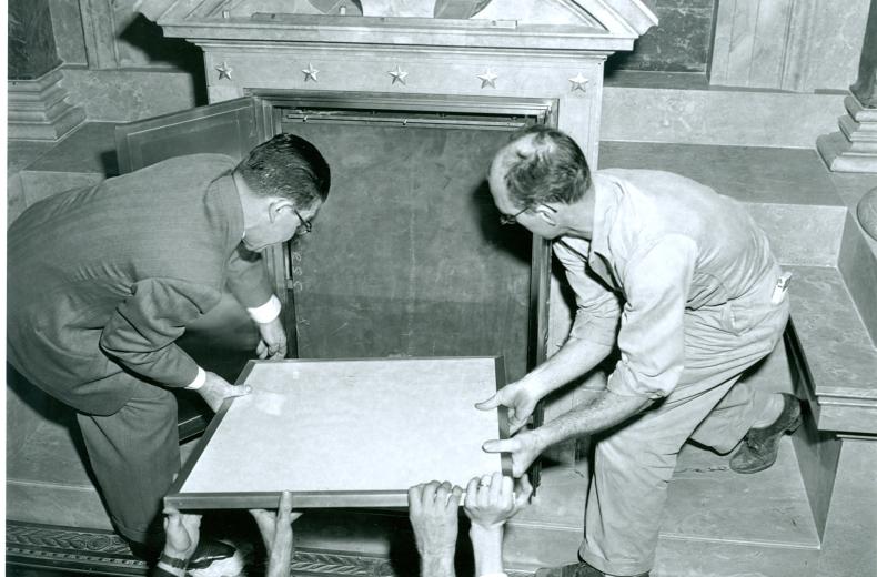Two men placing the Declaration of Independence into the new display case at the National Archives (Source: National Archives)