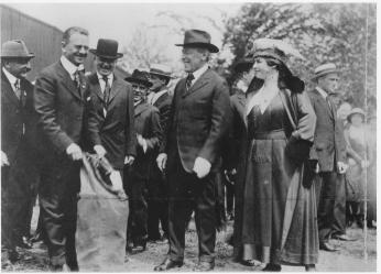 President Wilson, the First Lady, and other Post Office officials putting a letter in a mail bag for the U.S.' first inaugural airmail flight.