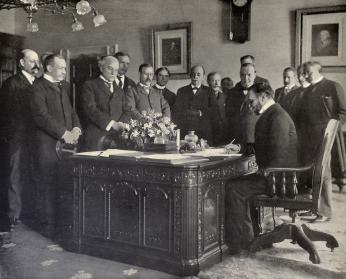 Black-and-white image of John Hay signing the Treaty of Paris.