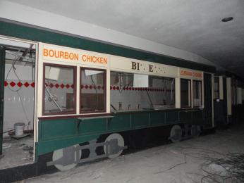 A decrepit food truck resembling a streetcar. Letters are falling off the signs.