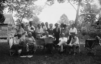 Henry Ford, Thomas Edison, Warren Harding, Harvy Firestone and their camping group with the log cabin in the background