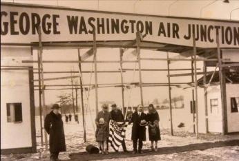 Black and white photo of Henry Woodhouse and guests standing in front of George Washington Air Junction entrance, from 1929-30.