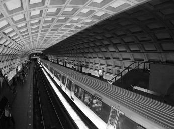 Black and white photo of concrete coffered ceiling of Metro station with train.