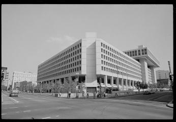 Black and white photo from 1977 of blocky concrete building in downtown D.C. intersection. 