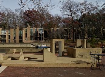 Photo of assorted concrete architectural elements rising out of ground in outdoor park-like setting.