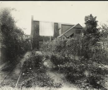 Exterior photo of Frances Benjamin Johnston's home and photo studio in Washington, DC, showing brick building with rose garden. (Source: Library of Congress).