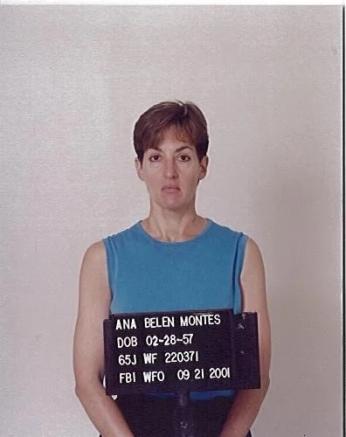 Mugshot of frowning woman with short hair and blue shirt holding a placard with her name, date of birth and FBI ID numbers.
