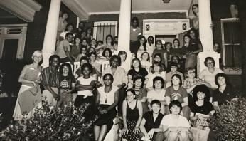 Black and white image of Sisterfire staff and volunteers gathered on a front porch posing.