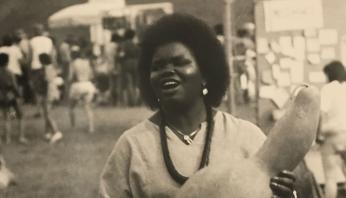 Black and white photograph of a Black woman holding a gourd. 
