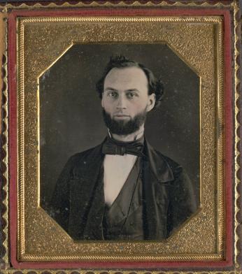 19th century black and white portrait of man with beard in gold frame. 